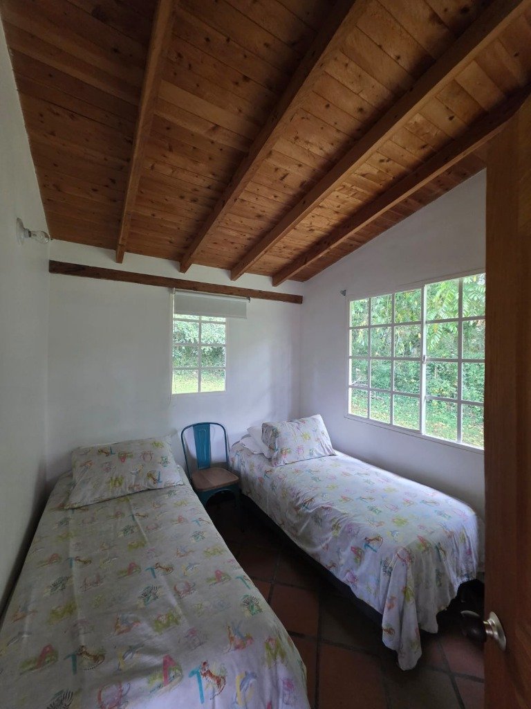 Segunda habitación amoblada con 2 camas confortables y ventana con vista a las montañas en Casa Campestre La Isabela, La Ceja
