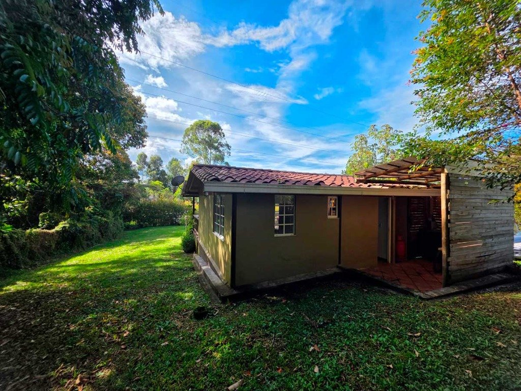 Costado de la casa campestre con tejado tradicional en teja de barro y prados verdes de 1.500 m² en Casa Campestre La Isabela, La Ceja